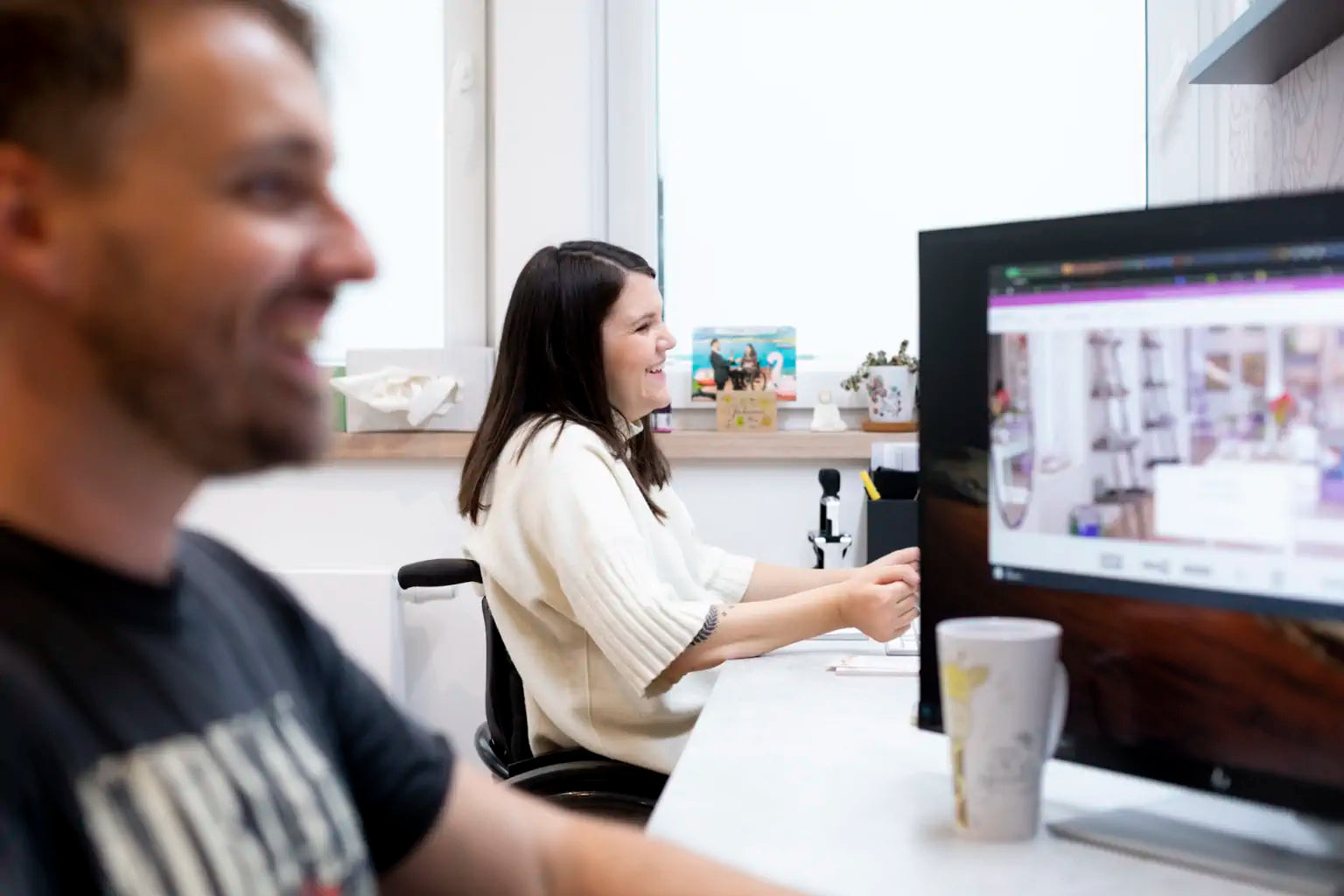 Tina und Richi sitzen im Büro vor den Computern und haben sichtlich Spaß