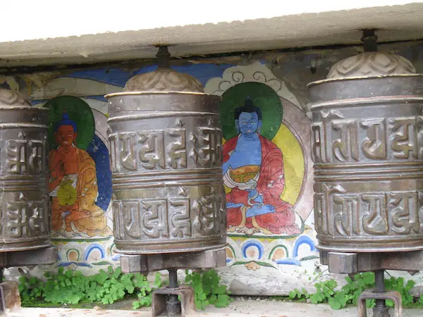 Gebetsmuehlen in Nepal mit farbigen Motiven im Hintergrund