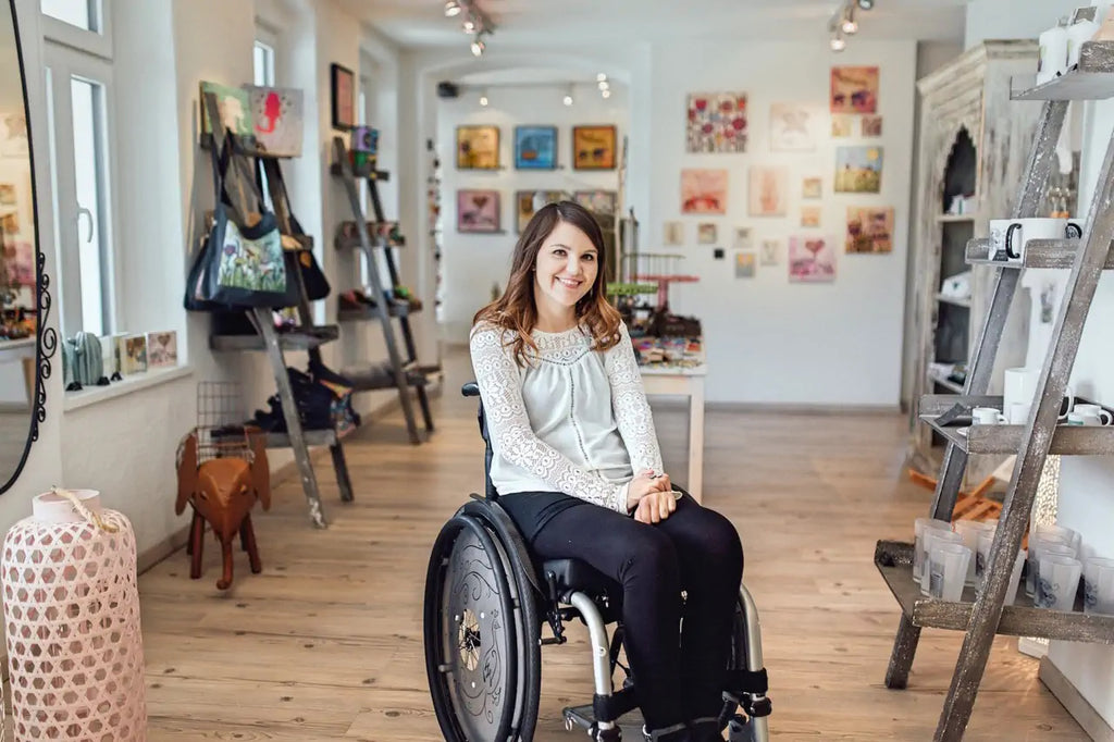Bild aus 2017. Tina sitzt im Rollstuhl in ihrer Galerie in St.Johann in Tirol